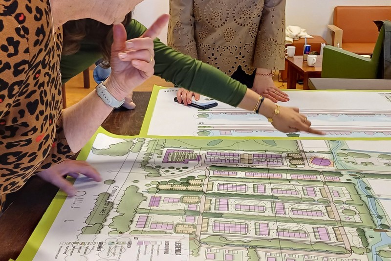 Mensen buigen over een kaart met plannen voor de nieuwe wijk Eschmarkerveld